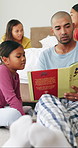 Reading, books and dad with children in bedroom for bonding with literature, story and novel. Morning, family and parents with kids in home for learning, knowledge and development for relationship