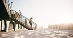 Headphones, athlete and running on stairs at beach for HIIT workout, endurance challenge or fitness. Sunshine, man and cardio on steps for athletic performance, exercise routine and music with space