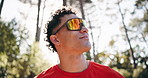 Fitness, thinking and man in woods, low angle and breathing with break, exercise and wellness. Sunshine, rest or person in forest, workout for health benefits or challenge with reflection or balance
