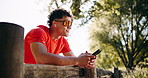 Fitness, smartphone and happy man with earphones in nature, wonder or texting with contact on break. Outdoor, music and person with mobile for message, streaming and smile after exercise at park