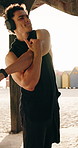 Man, fitness and stretching with headphones on beach for workout preparation or exercise. Active, male person or getting ready with sun or body warm up for outdoor training on ocean coast in nature