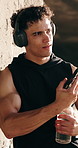 Fitness, phone and headphones with man outdoor for runner stats, health app and streaming. Music, drinking water and wellness with person for communication, training plan or monitor progress
