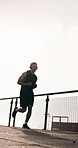 Running, city and man with headphones and smart watch for exercise, cardio and workout with music. Town, athlete and person check time for health, wellness and training with audio, radio and track