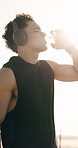 Fitness, water and man with headphones in morning for hydration after exercise, workout and training. Sunlight, runner and person with bottle for electrolytes, wellness and hydration with music
