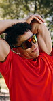 Stretching, athlete and man with headphones at park, breathing and listening to podcast for fitness. Outdoor, runner and person with workout  routine for health, training or streaming audio with tech