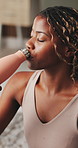 Yoga, woman and drinking water in house with break, wellness or natural detox for holistic health. Thirsty, black person and exercise recovery in home with bottle, nutrients or beverage for hydration