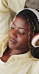 Woman, peace and relax on sofa with headphones, stretching and calm music playlist to chill on weekend. Black person, rest and self care in home with audio tech, wellness or listen to online podcast.