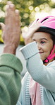High five, parent and girl with helmet in backyard, safety practice and support for cycling lesson. Smile, protection gear or person with child to learn responsibility, getting ready or bokeh by home
