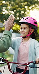 High five, father or girl with bike helmet in backyard, safety practice or support for riding lesson. Smile, protection gear and man with child to learn responsibility, getting ready or bokeh by home