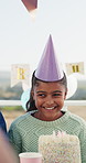 Birthday, happy and child with cake at party for celebration, special day and thinking of wish outdoor. Family, excited and girl with decorations, hat and candles for event, gathering and milestone