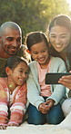 Parents, children and selfie on picnic blanket at park, smile and bonding on family vacation in summer. People, mom and dad with kids, photography and happy with memory for social media on holiday