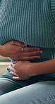 Stomach pain, sofa and woman in home with endometriosis, constipation or menstruation symptoms. Belly ache, sick and female person with abdominal cramps for ibs, indigestion or diarrhea in house.