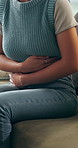 Stomach pain, sofa and woman in house with menstruation, constipation or endometriosis symptoms. Belly ache, sick and female person with abdominal cramps for ibs, indigestion or diarrhea in home.