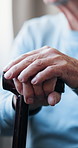 Hands, cane and injury in home for retirement with rest, recovery and mobility aid in living room. Senior person with disability, walking stick and break in lounge with rehabilitation at house