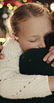 Christmas, mother and daughter with hug in home, support and family bonding for festive season cheer. Embrace, love and woman with happy child for holiday celebration, bokeh and security in apartment