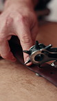 Hands, leather and hole punch for belt, manufacturing and production process in workshop with tools. Person, tannery and piercing strap for fashion, creative craft and textile in small business