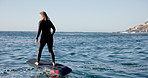 Ocean, blue sky and woman on electric surfboard for active, workout or water sports on vacation. Travel, fitness and female person on efoil by sea for exercise, training or surfing on holiday.