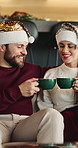 Christmas, cheers and couple in home, smile and tradition with eggnog, celebration and festive season. Cacao, man and woman on sofa, Xmas holiday and bonding together with hats, talking or happiness