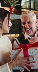 Christmas, gift and father in home, woman and celebration for festive season, parent and adult daughter. Smile, family and mature man in lounge, present for Xmas and happiness for tradition or relax