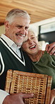 Christmas, hug and senior couple with basket in home, holiday celebration and funny conversation for bonding. Support, embrace and elderly people with smile for festive season, connection and laugh