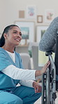 Bonding, nurse and old person in center with wheelchair, friendly discussion and support in retirement care. Smile, caregiver and patient with disability, connection and empathy in nursing home.