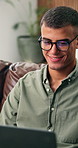 Man, laptop and happy on sofa for remote work from home, glasses and review for article in living room. Person, freelance writer and smile with computer, feedback or story development at apartment