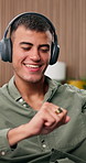 Headphones, cellphone and man in lounge, dancing and listening to music, internet and relax. Happiness, energy and person in home, smartphone and streaming for radio, audio and digital app for song