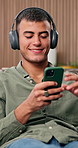 Headphones, cellphone and man in home, relax and listening to music, internet and audio. Happy, mobile user and person in lounge, smartphone and streaming for radio and wellness app for podcast