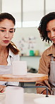 Women, discussion and pottery wheel in workshop for production, manufacturing process or check notes. Ceramic studio, creative and mature people with mug for art design, teamwork and handcraft