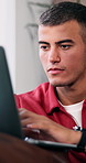 Laptop, relax and man on sofa in home with online application for university with scholarship. Technology, typing and male student with computer for email with college results in living room at house