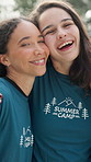 Volunteers, face and laugh with hug at summer camp for bonding, community service or solidarity. Workers, women or happy team on campground for volunteering, holiday program support or about us pride