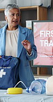 Woman, presentation and training with bag for first aid with teaching, advice and screen at office. Mature person, coach and workshop with smile, monitor or explain info for emergency in workplace