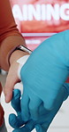 Hands, first aid and training with bandage at office, teaching and staff workshop with gloves for help. Person, coach and cloth in workplace with gauze, learning and demonstration for emergency