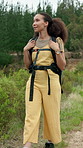 Woman, hiking or journey with backpack in nature for outdoor travel, sightseeing trip or fitness. Active, female person or hiker walking with bag on path or trail for trekking adventure in wilderness