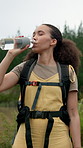 Woman, drinking and water with backpack for hiking break, recovery or hydration in nature. Female person, mineral and liquid with hiker gear, beverage or rest for natural sustainability or trekking