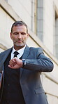 Check, time and businessman in city for commute, lawyer or travel to court case, serious and morning. Corporate, mature attorney and person with watch on street, journey and walk to trial appointment