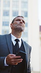 City, businessman and waiting for taxi with phone, serious or commute to business meeting in morning. Outdoor, entrepreneur and mature person with mobile for communication, travel and transport delay