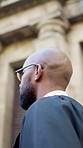 Black man, judge and walk to court in town with gown, glasses or legal career for judicial services. African person, magistrate or attorney with law, robe and perspective with low angle in city