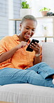 Laugh, message and black woman on couch with phone, online communication and meme post on social media. Happy, digital and person in house with tech, funny text or gif reaction on chat app.
