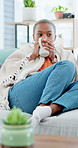 Coffee, relax and black woman on home sofa for thinking, warm beverage and chill on weekend. African person, tea cup and couch in house living room with blanket for unwinding and rest with drink