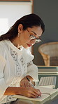 Creative, glasses and woman with notebook in home office, serious and planning for novel publication. Author, remote work and mature person with journal, writing and brainstorming for book release