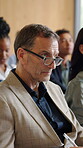 Audience, man and listening with notes in seminar for finance expo, knowledge or staff upskill. Conference, crowd and mature person with glasses for financial literacy, wealth management and learning