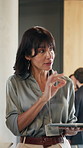Businesswoman, speaking and networking at convention center with tablet, seminar agenda and trade show. Mature person, event organizer and tech at conference with expo feedback, advice and schedule.