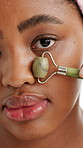 Jade roller, beauty and face of black woman in studio for wellness, skincare and facial treatment. Dermatology, portrait and person with tools for circulation, massage and health on white background