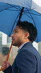 Businessman, umbrella and travel in town with rain, thinking or cold on walk for property development. Person, real estate agent and parasol for perspective, briefcase and career with winter in city