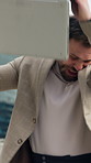 Angry, businessman and throwing laptop in city for bad news, destruction and violent outburst. Frustrated, male person and breaking pc with series, equipment vandalism and aggression reaction outdoor