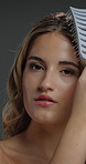 Studio, face and woman with hairbrush for haircare, serious or cosmetics for healthy natural texture. Gray background, makeup and person with tool for hair growth, grooming and beauty in Canada