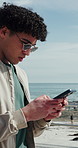 Ocean, walking and man with phone, internet for online chatting and map for directions. Outdoor, mobile user and person with tech for social media, network and connection for communication in Miami