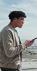 Beach, walking and man with phone, internet for online chatting and map for location. Ocean, mobile user and person with tech for social media, summer holiday and connection for direction in Miami
