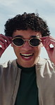 Travel, man or laughing with sunglasses at beach for funny holiday, positive energy or weekend break. Tourist, person and shades with joke on promenade for vacation trip, getaway and ocean fresh air